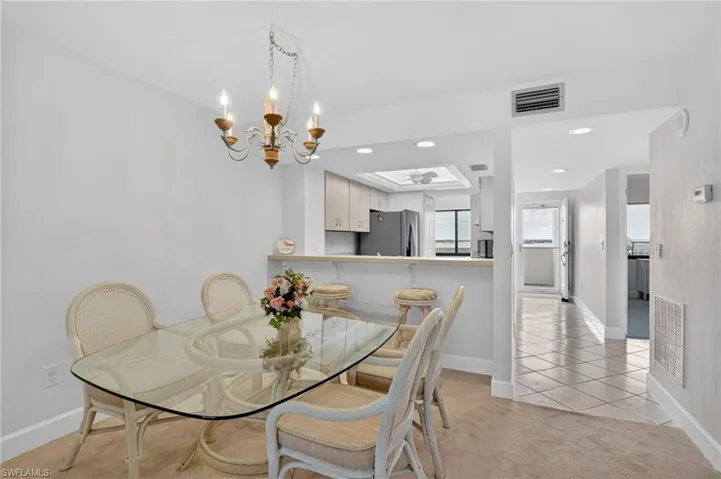 Dining area with light tile patterned floors, light carpet, and suspended lighting