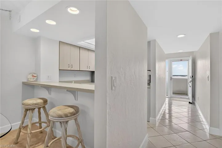Hallway featuring recessed lighting, light tile patterned floors, and a textured wall