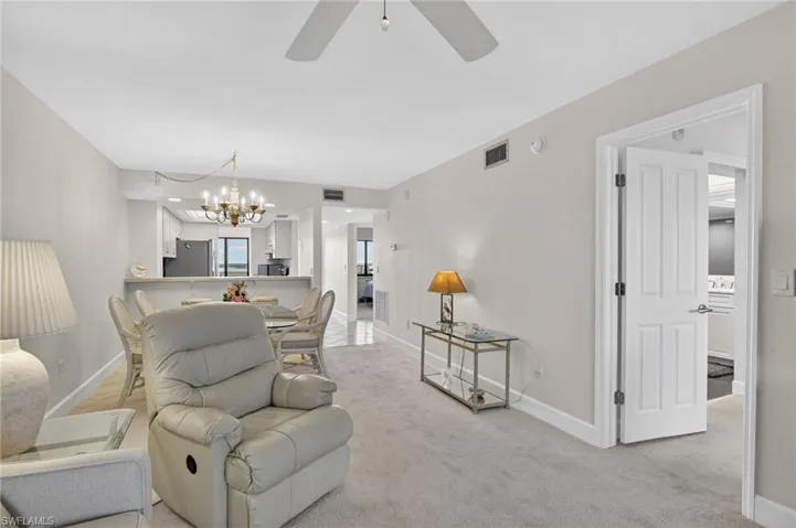 Living room with suspended lighting, light colored carpet, and a ceiling fan
