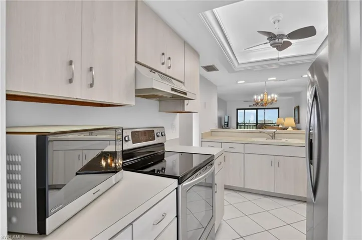 Kitchen featuring stainless steel appliances, light countertops, a ceiling fan, hanging lights, and ornamental molding