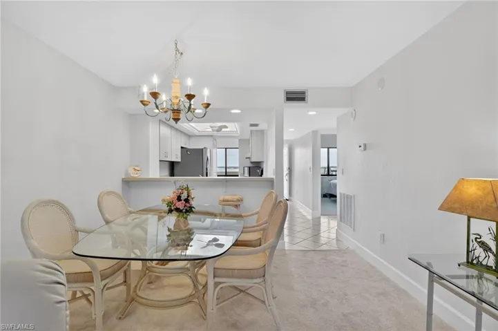 Dining space featuring suspended lighting, light colored carpet, and light tile patterned floors