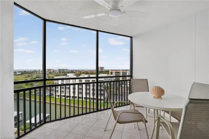 Sunroom / solarium featuring a balcony, ceiling fan, and a water view