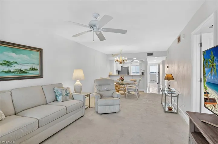 Living room with ceiling fan, a chandelier, and light colored carpet