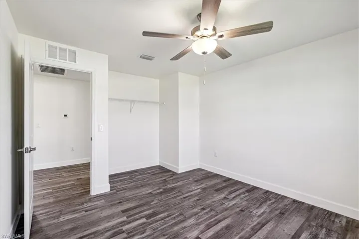 Unfurnished bedroom featuring a closet, dark wood-type flooring, and ceiling fan
