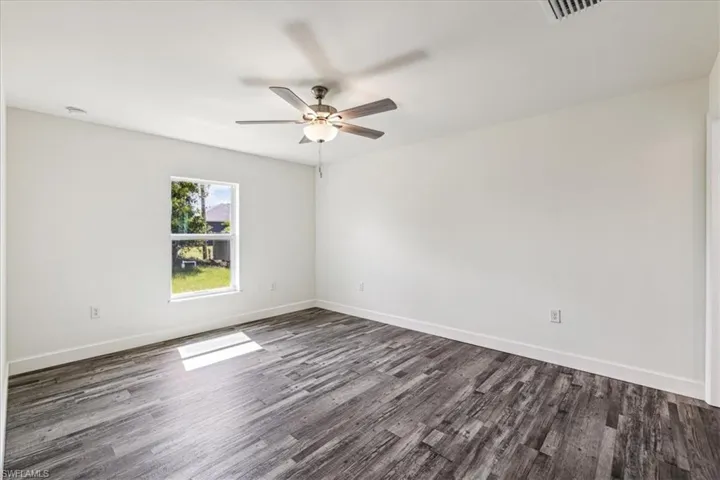 Unfurnished room with ceiling fan and dark hardwood / wood-style flooring