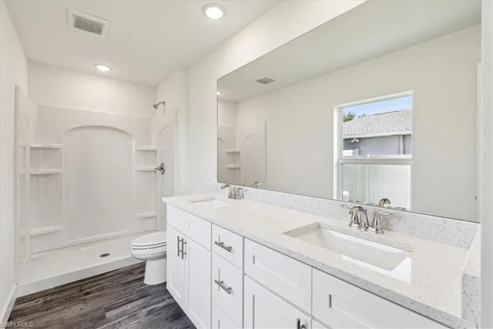 Bathroom featuring toilet, hardwood / wood-style flooring, vanity, and a shower