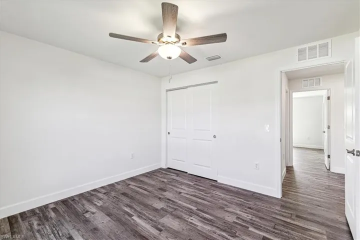 Unfurnished bedroom with dark wood-type flooring, ceiling fan, and a closet