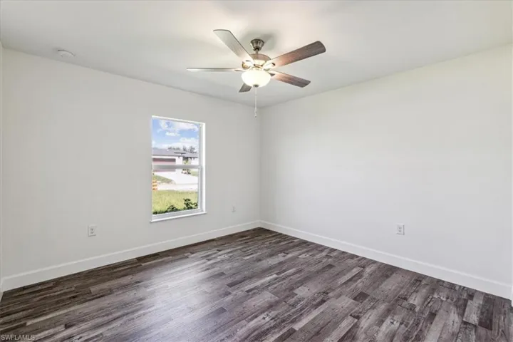 Empty room with ceiling fan and dark hardwood / wood-style flooring