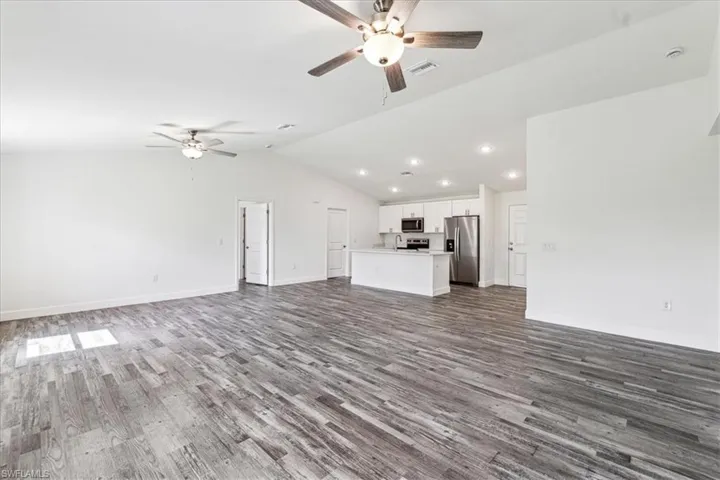 Unfurnished living room featuring hardwood / wood-style flooring, ceiling fan, and vaulted ceiling