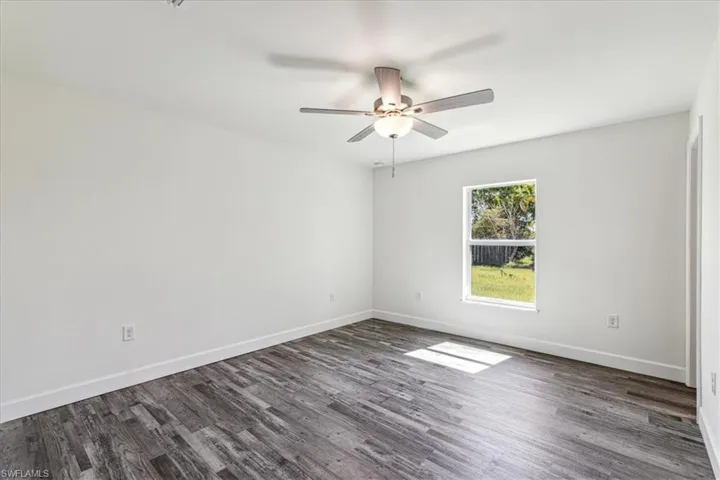 Unfurnished room with ceiling fan and dark hardwood / wood-style flooring