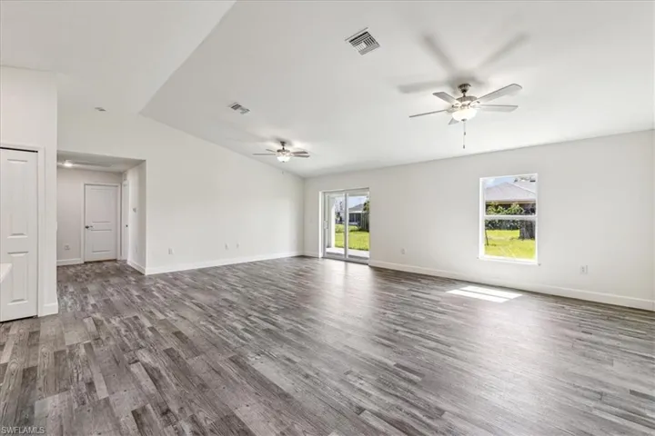 Unfurnished living room featuring hardwood / wood-style flooring, ceiling fan, vaulted ceiling, and a wealth of natural light