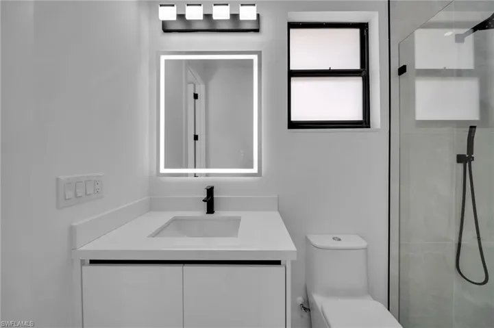 Full bathroom featuring toilet, vanity, and a stall shower
