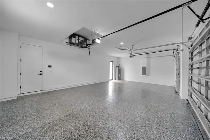 Garage with a garage door opener, recessed lighting, and gas water heater
