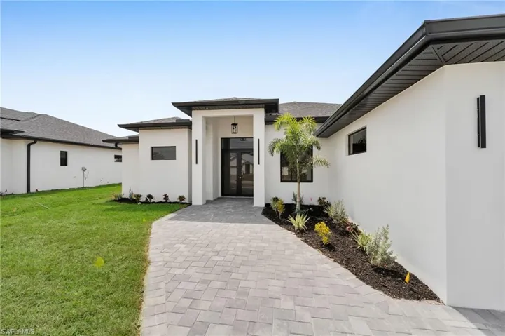 Entrance to property featuring french doors, stucco siding, and a lawn