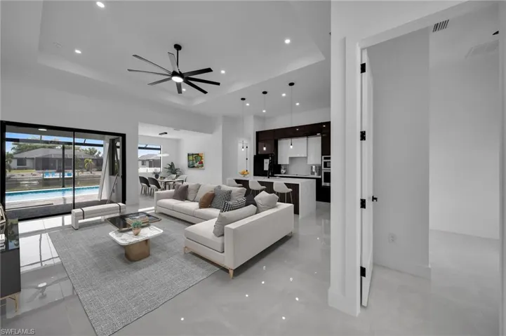 Living room with baseboards, a tray ceiling, recessed lighting, and a ceiling fan