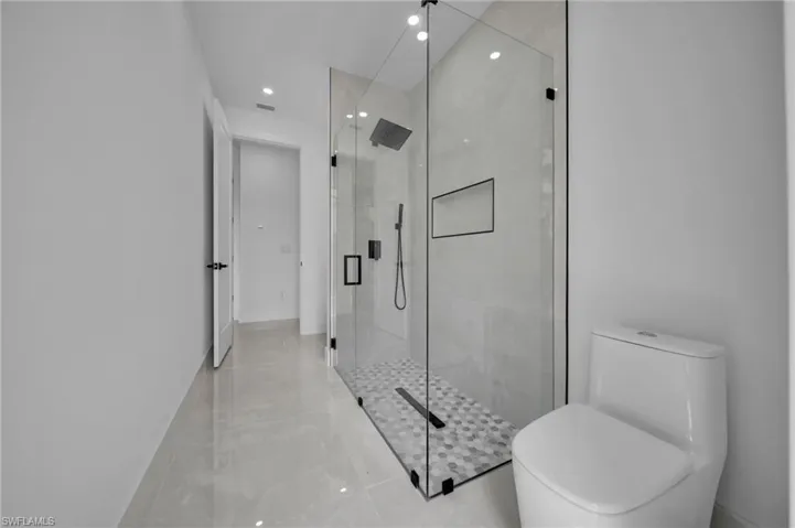 Bathroom with a shower stall, visible vents, toilet, and recessed lighting