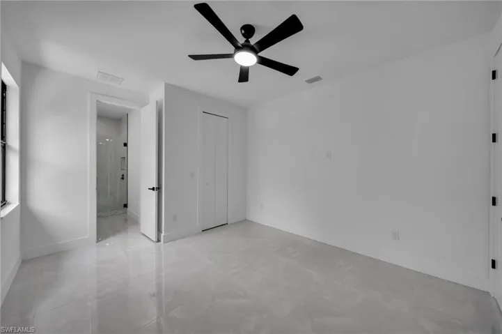 Unfurnished bedroom featuring baseboards, visible vents, ensuite bath, and a ceiling fan