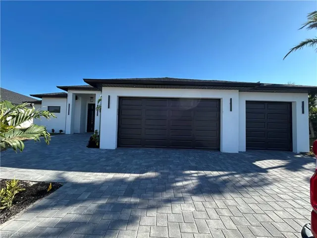 Prairie-style home featuring a lawn, decorative driveway, an attached garage, and stucco siding