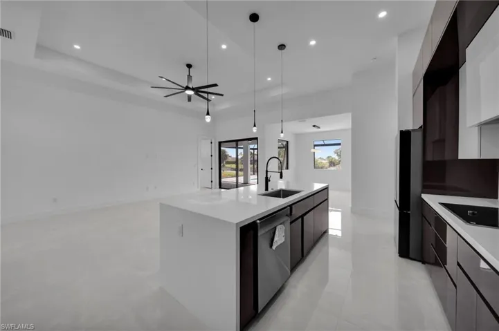 Kitchen with modern cabinets, a sink, light countertops, and black appliances