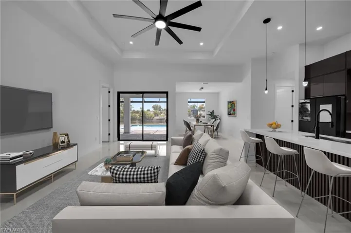 Living area with ceiling fan, a high ceiling, recessed lighting, and a raised ceiling