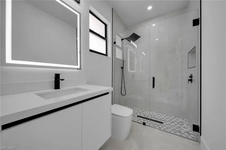 Bathroom featuring vanity, marble finish floor, toilet, and a shower stall