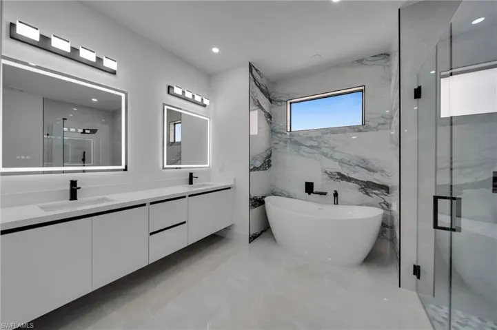 Full bath featuring double vanity, a sink, a freestanding tub, and a shower stall
