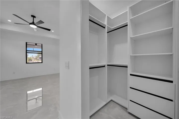 Walk in closet featuring marble finish floor and ceiling fan