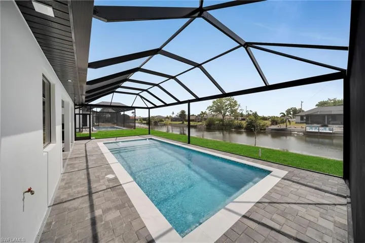 Outdoor pool with a patio, a water view, a yard, and a lanai
