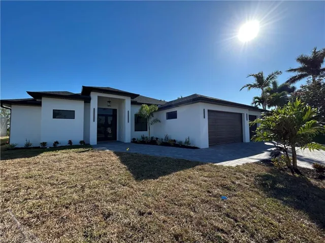 Prairie-style home featuring a front yard, driveway, stucco siding, and an attached garage
