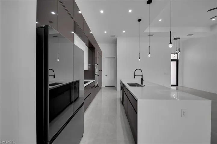 Kitchen featuring a large island with sink, a sink, modern cabinets, and stainless steel appliances