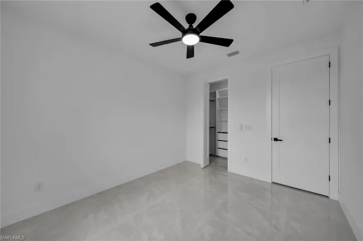Unfurnished bedroom featuring a spacious closet, baseboards, ceiling fan, and visible vents