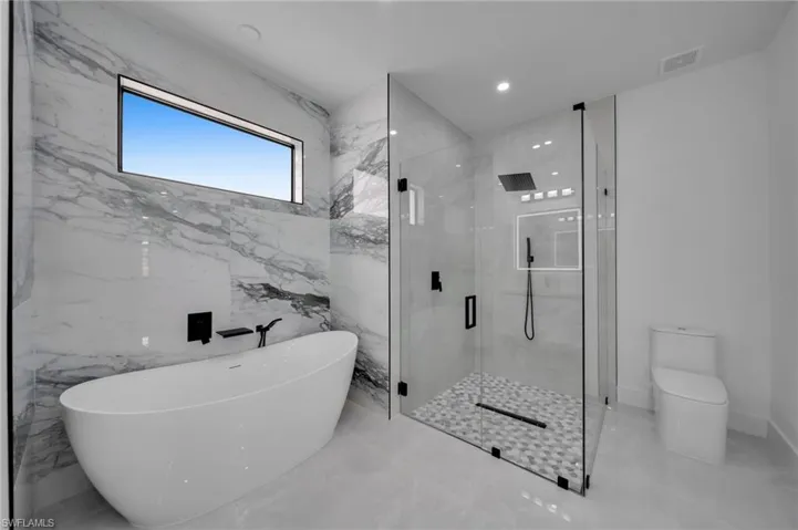 Full bath featuring a soaking tub, marble finish floor, a marble finish shower, and visible vents