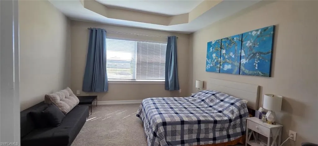 Carpeted bedroom with baseboards and a raised ceiling