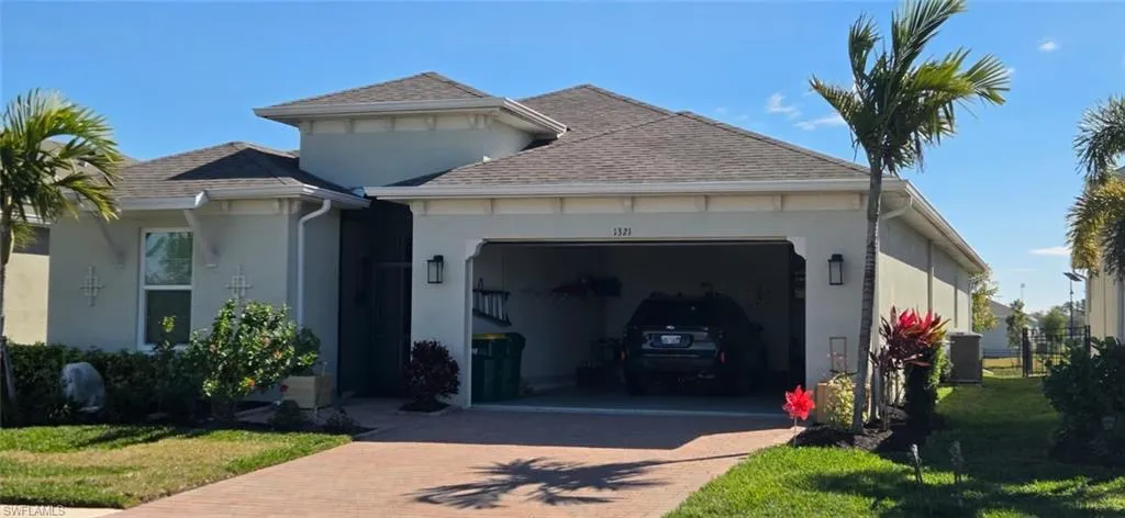 View of front of house featuring a garage, a shingled roof, decorative driveway, and a front lawn