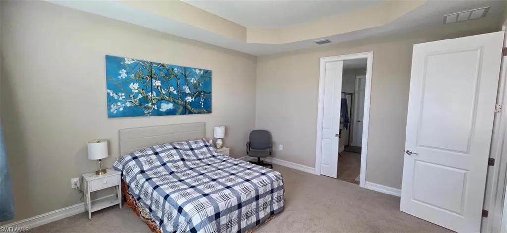 Bedroom with a tray ceiling and light colored carpet
