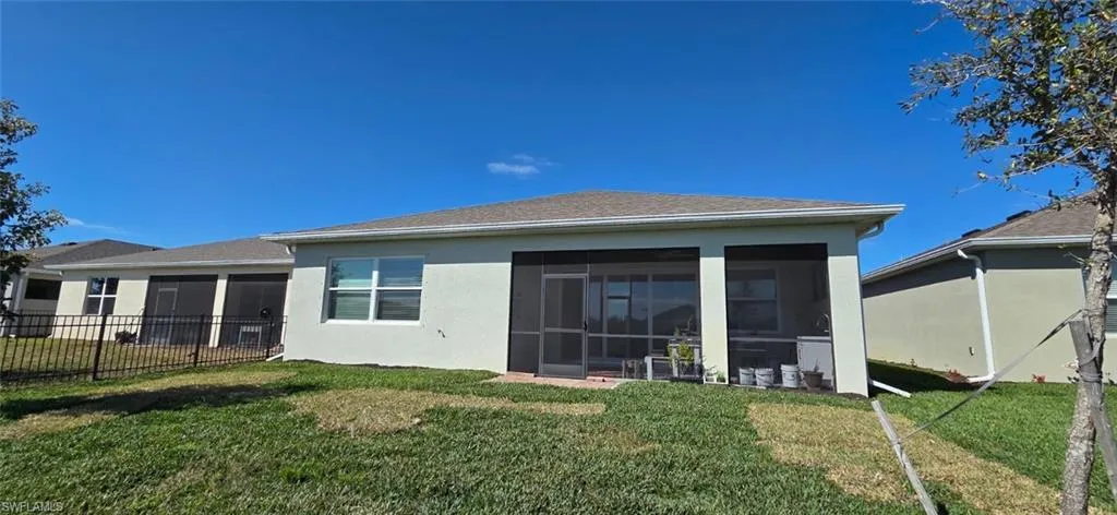 Back of house featuring stucco siding, a yard, and a sunroom
