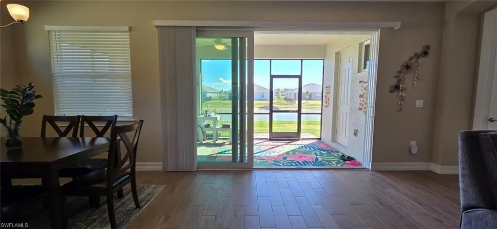 Doorway to outside with wood finished floors, a water view, and a residential view