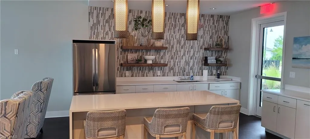 club house Kitchen featuring open shelves, freestanding refrigerator, white cabinetry, and a kitchen bar