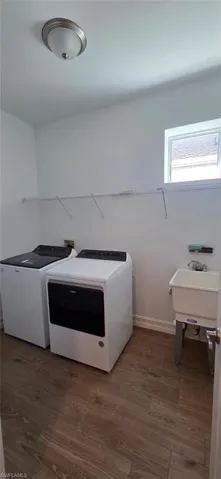 Laundry room with dark wood-style flooring and washer and clothes dryer