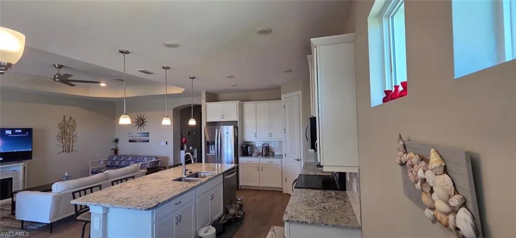 Kitchen with white cabinetry, open floor plan, and light stone counters