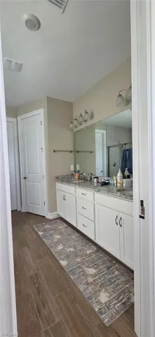 Bathroom with double vanity and dark wood-type flooring
