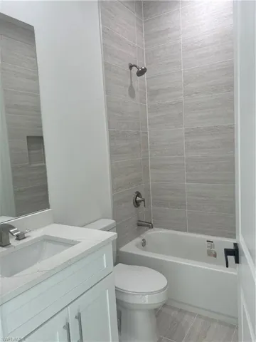 Full bathroom featuring vanity, tiled shower / bath, and toilet