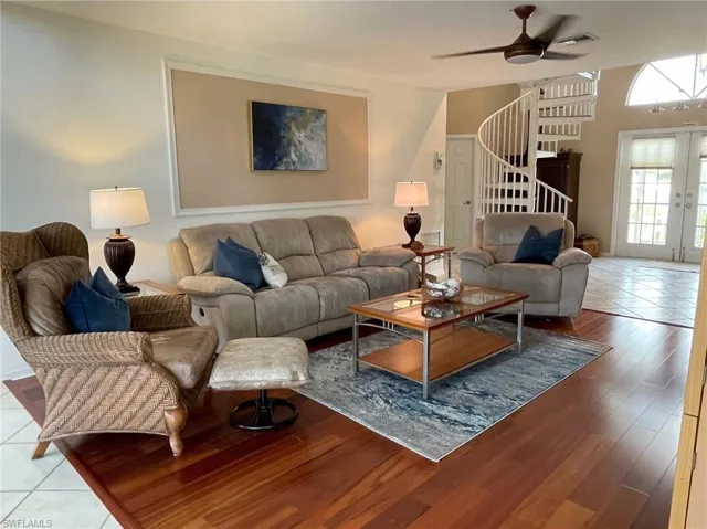 Tiled living room featuring a ceiling fan and french doors