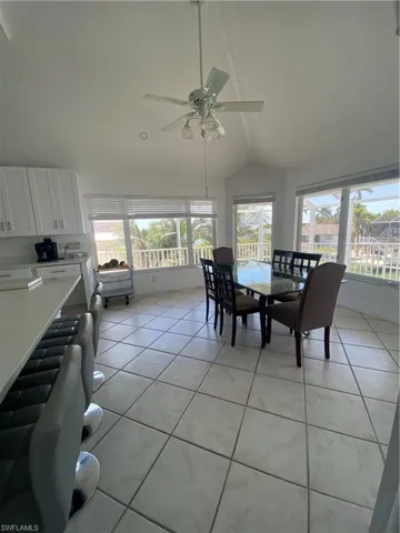Dining space featuring lofted ceiling, light tile patterned flooring, radiator heating unit, and a ceiling fan