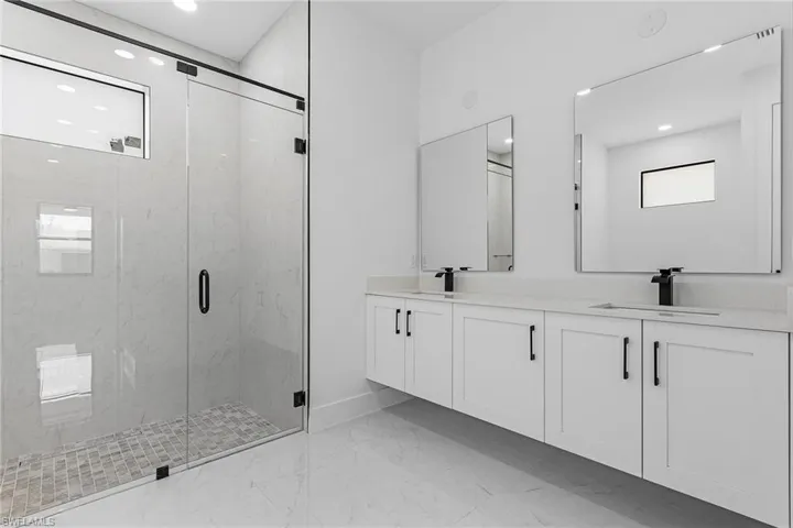 Full bathroom featuring marble finish floor, a sink, a marble finish shower, and double vanity
