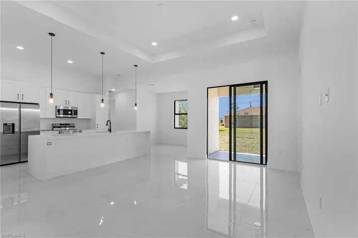 Kitchen featuring white cabinets, marble finish floor, a raised ceiling, appliances with stainless steel finishes, and a sink