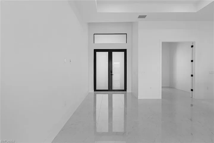 Spare room featuring marble finish floor, baseboards, visible vents, and a tray ceiling