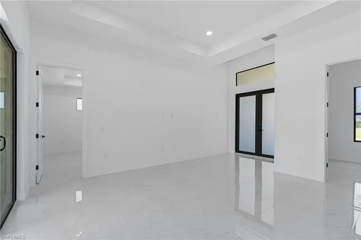 Unfurnished room featuring marble finish floor, visible vents, french doors, and a raised ceiling