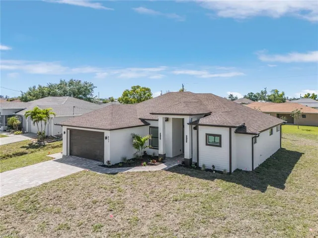 Ranch-style home featuring stucco siding, a front lawn, a shingled roof, decorative driveway, and a garage