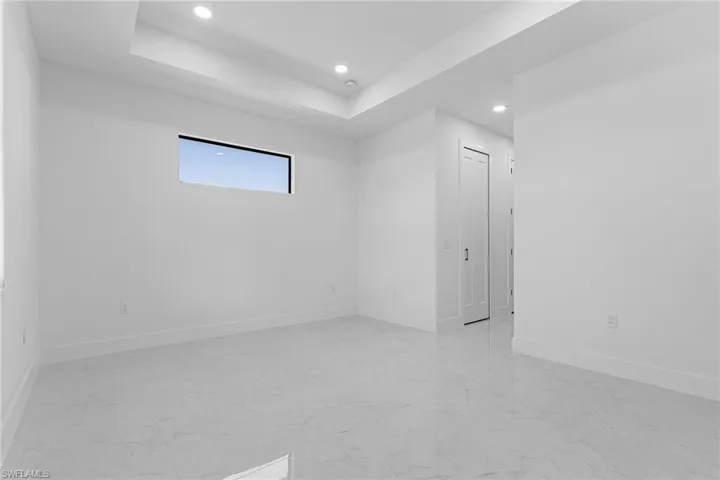Spare room featuring a tray ceiling, baseboards, marble finish floor, and recessed lighting